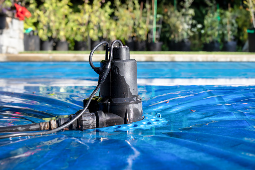 Perspective view of black pool cover pump for keeping the water away from pool covers or spas. Selective focus.