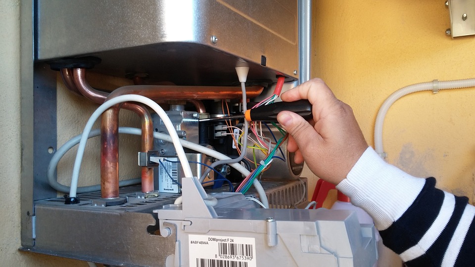 person holding a screw driver and fixing a boiler