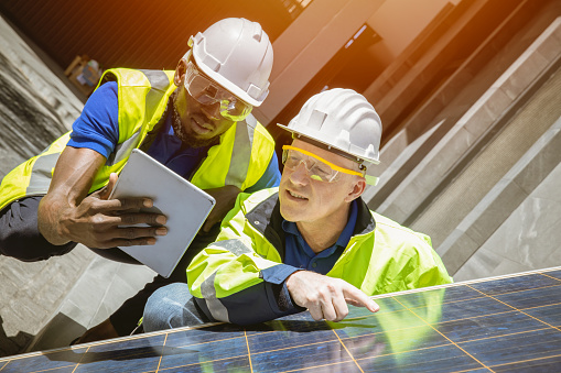 Solar cell engineer teamwork working together to install and check solar panel at rooftop