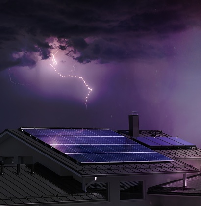 Solar panel system on house roof, dark sky, thunder and lightning background