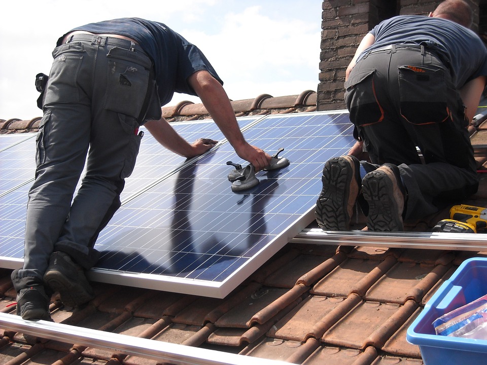 two solar contractors installing solar PV panels on a slate rooftop in Orlando Florida